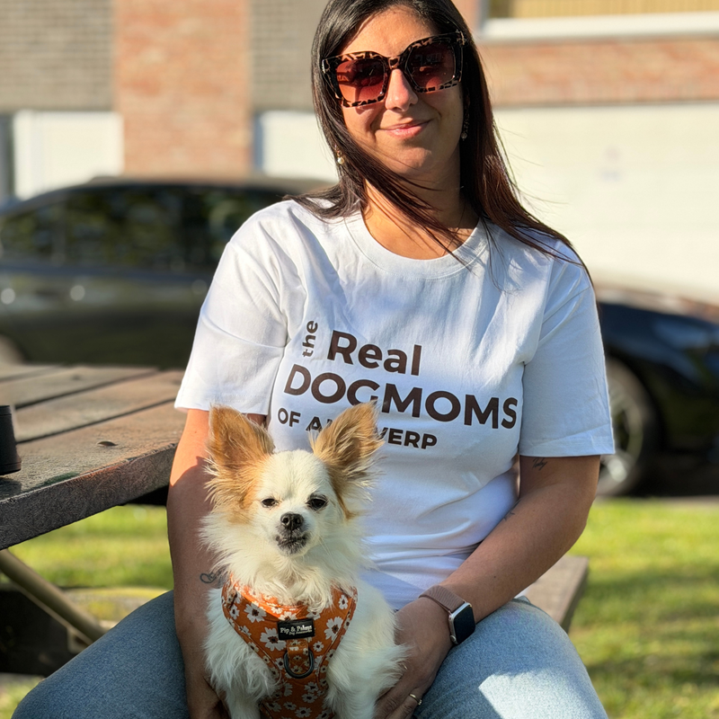 Vrouw draagt het witte The Real Dogmoms of Antwerp T-shirt terwijl ze met haar hond poseert